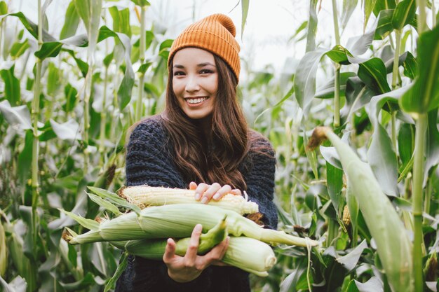 Beautiful asian girl wearing yellow hat and knitted sweater in autumn corn field. 