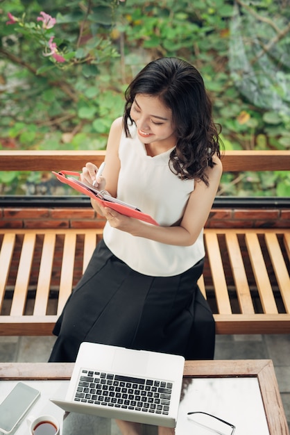 Beautiful asian girl writing notes in a desk at home