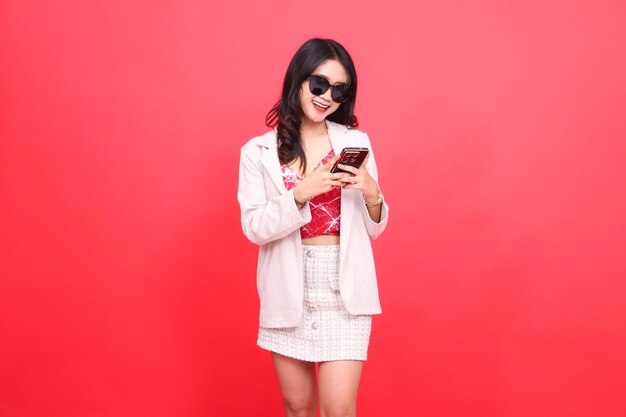 Beautiful asian indonesian woman wearing glasses cheerfully slanted to the left operates a cellphone