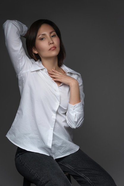 대형 흰색 셔츠를 입고 사진 스튜디오에서 포즈를 취하는 아름다운 아시아 모델