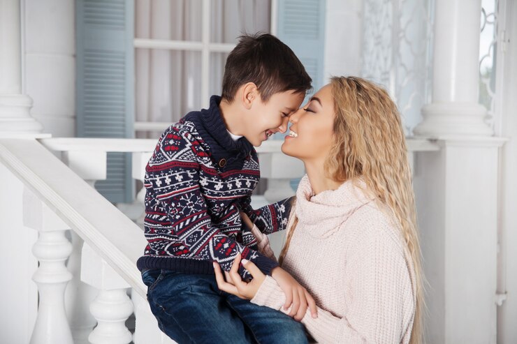 Photo beautiful asian  mother hugging with her little son on the white front porch of a country vacation house. 