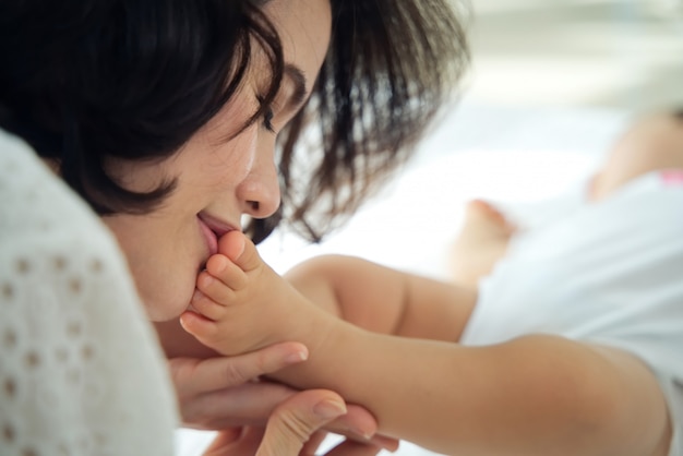 아이가 자고있는 동안 눈을 감고 그녀의 아기 발을 키스하는 아름다운 아시아 어머니