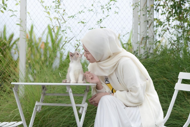 屋外で彼女の猫と遊ぶ美しいアジアのイスラム教徒の猫の恋人