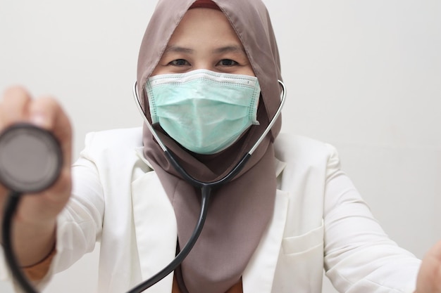 Photo beautiful asian muslim female medical doctor wear mask examination stethoscope smiling to camera