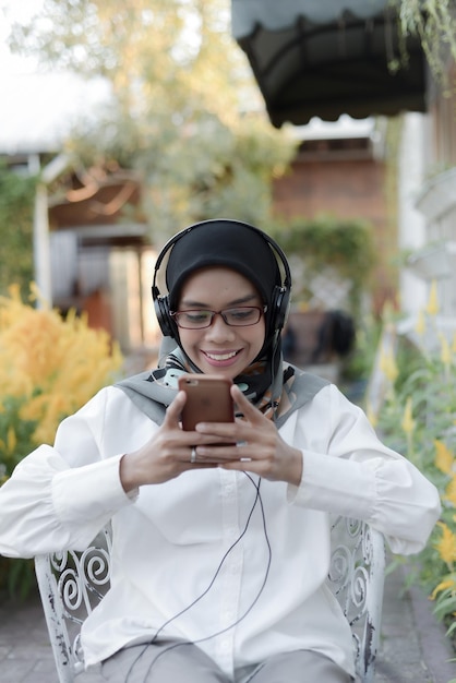 beautiful asian muslim lady casual using headphone and listen music