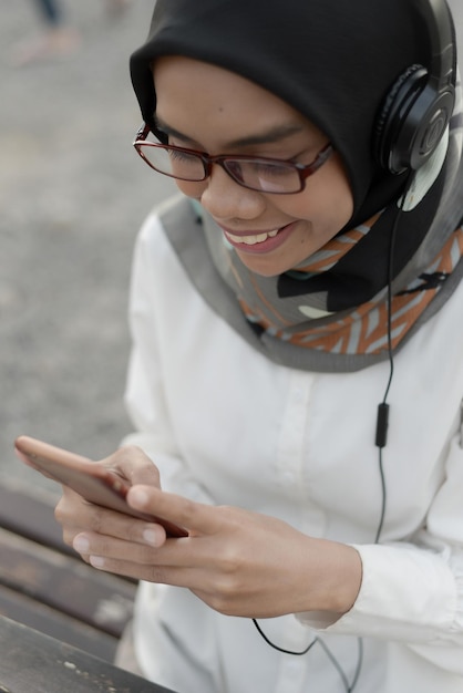 Photo beautiful asian muslim lady casual using headphone and listen music