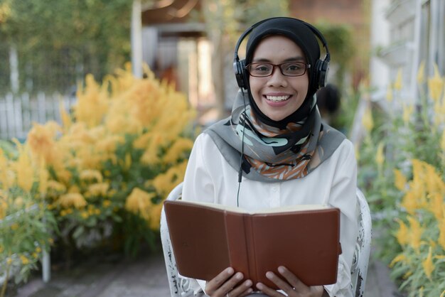 beautiful asian muslim lady casual wear read a book and using headphone