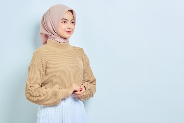 Beautiful Asian muslim woman in brown sweater smiling happy and looking confident isolated over white background People religious lifestyle concept