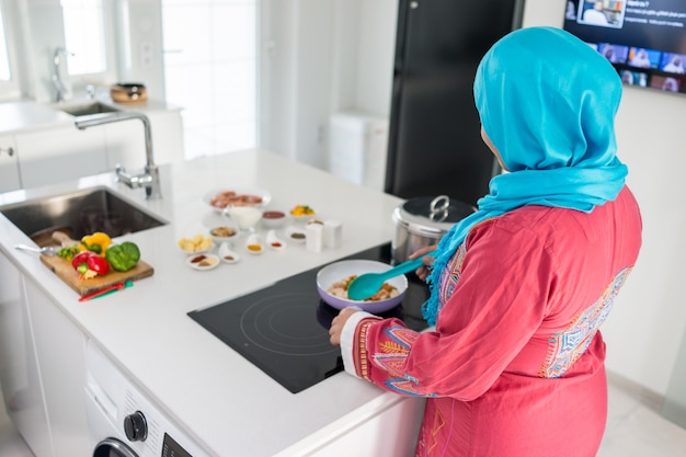 beautiful asian muslim woman smile while looking to the camera in the kitchen isolated white background