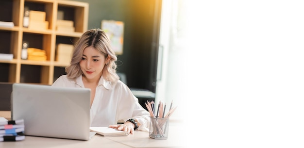 Sorriso del manager della bella donna d'affari del ritratto asiatico che lavora in ufficio con un computer portatile nell'ufficio moderno che si siede comunicazione finanziaria di marketing onlinexa