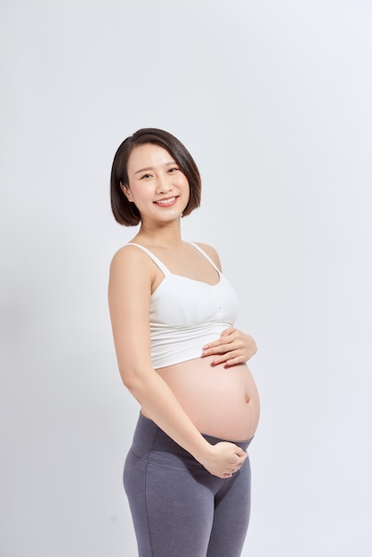 赤ちゃんを期待し、彼女の腹に触れる美しいアジアの妊婦