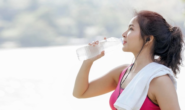 운동 후 물을 마시는 아름다운 아시아 운동가 또는 야외 복사 공간