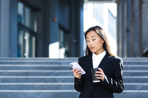 A beautiful Asian student uses the phone near the university campus