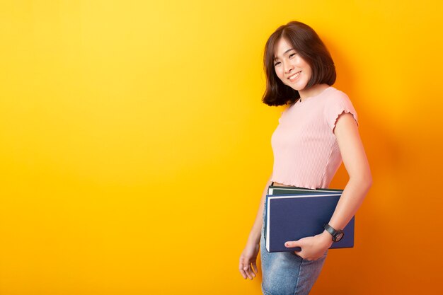 Beautiful asian student on yellow wall