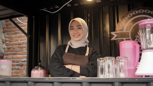 Beautiful asian waitress with arms looks cool guarding cafe booth container