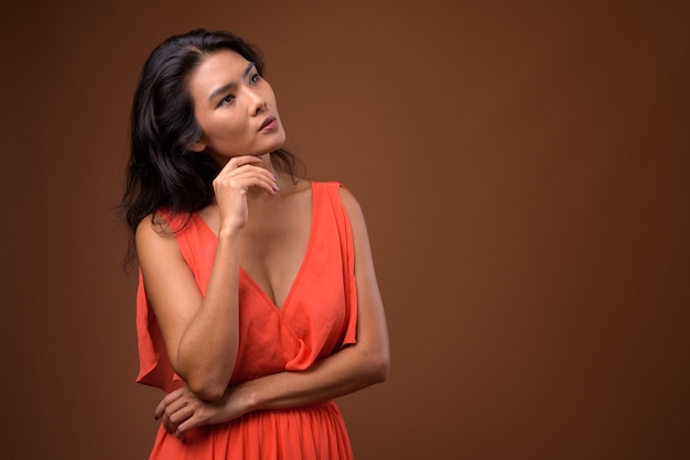 beautiful Asian woman against brown wall