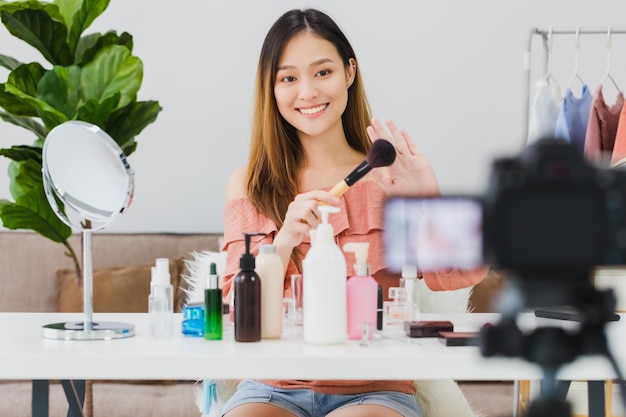 Фото Красивая азиатская женщина-блогер показывает, как наносить и использовать косметику перед камерой и записывает видео влог в прямом эфире дома уход за кожей для концепции здорового лица