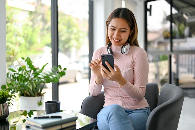 Beautiful Asian woman chatting with her friend on social media on her phone