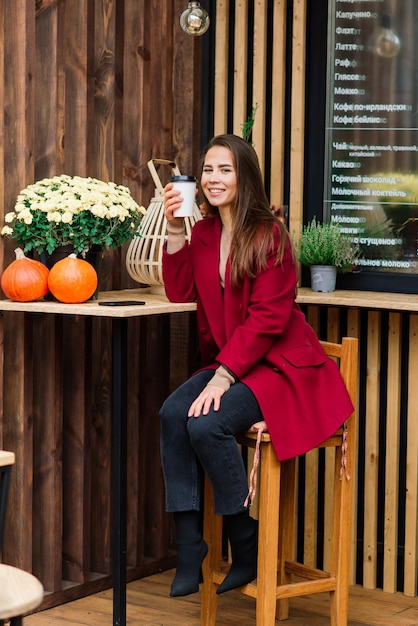 カフェでコーヒーを飲んで、笑顔で、電話で話している美しいアジアの女性