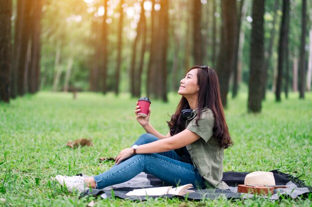 公園に座ってコーヒーを飲む美しいアジアの女性