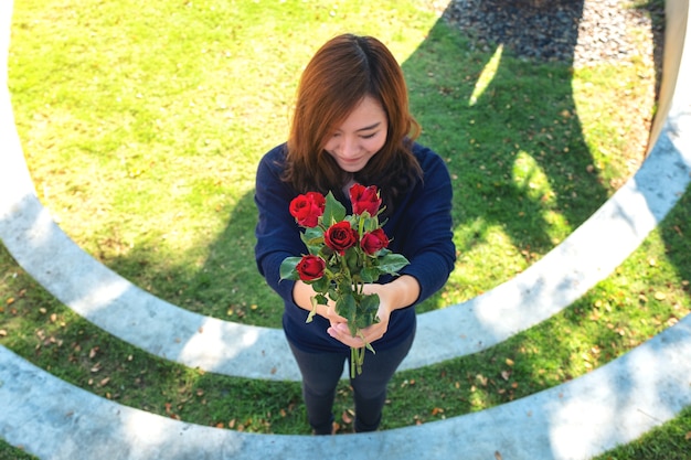 A beautiful asian woman giving red roses flower to her boyfriend on Valentine's day with feeling happy and loved