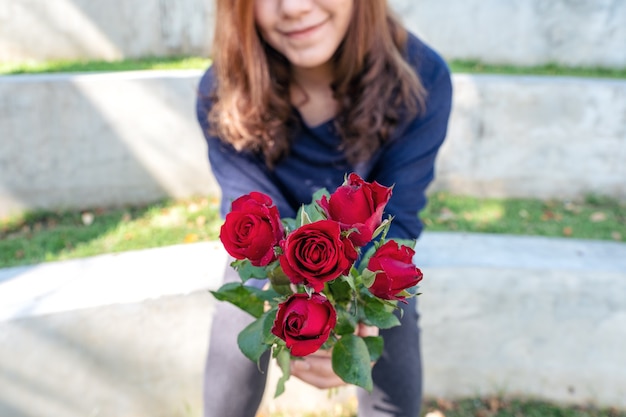 A beautiful asian woman giving red roses flower to her boyfriend on Valentine's day with feeling happy and loved