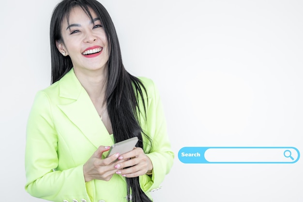 Beautiful Asian woman in green suit pastel holding smart phone and smiling isolated on white background Happy joyful girl with celebrating victory Asian woman successful happiness