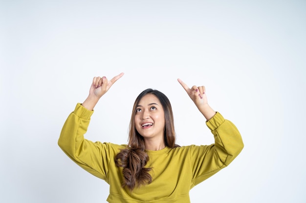 Foto bella donna asiatica in maglietta verde che punta le dita verso l'alto
