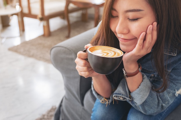 美しいアジアの女性を保持し、カフェでホットコーヒーを飲む