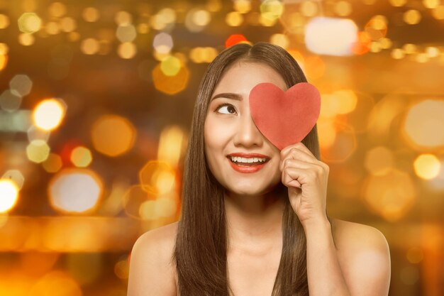 Beautiful asian woman holding red heart shaped