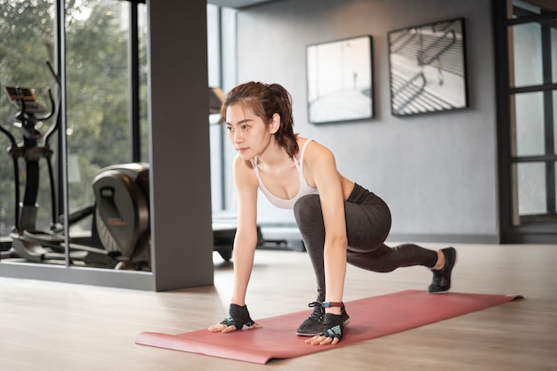 La bella donna asiatica sta facendo l'esercizio in palestra