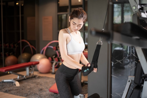 La bella donna asiatica sta facendo l'esercizio in palestra