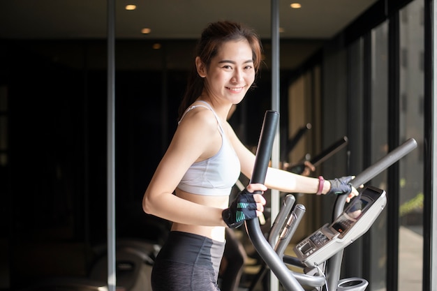 La bella donna asiatica sta facendo l'esercizio in palestra