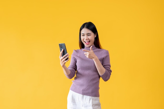 A beautiful Asian woman is pointing her finger at her phone screen and looking with a happy face