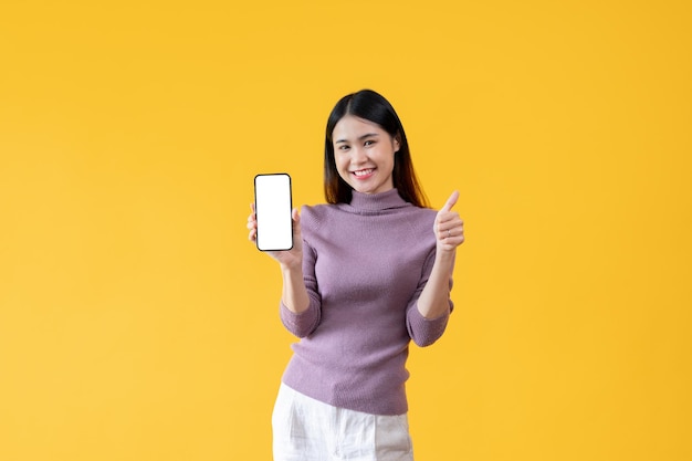 A beautiful Asian woman is showing her thumb up and the white screen of a smartphone to the camera