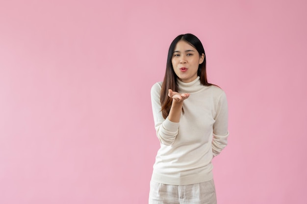 美しいアジアの女性がキスを吹き飛ばしキスのジェスチャーを送っています