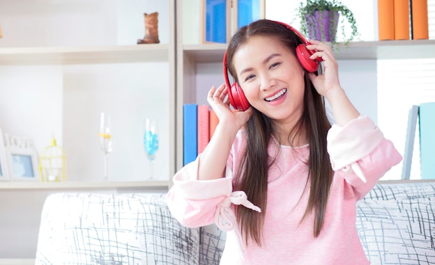 Красивая азиатская женщина слушая к музыке с наушниками