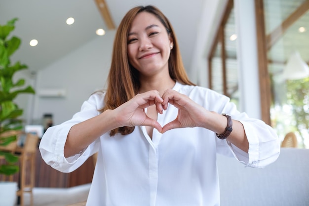 A beautiful asian woman making heart hand sign with feeling happy