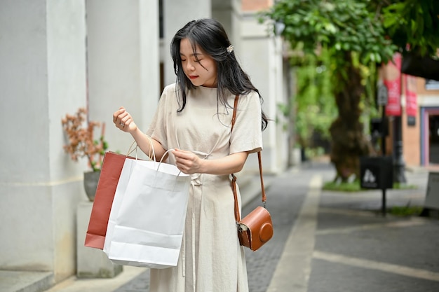 A beautiful Asian woman opening her shopping bag checking her purchased stuff