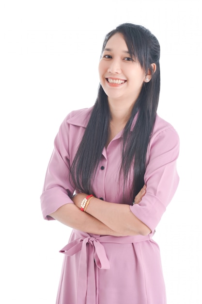 Beautiful asian woman in pink dress doing crossed arm and smiling over white space.