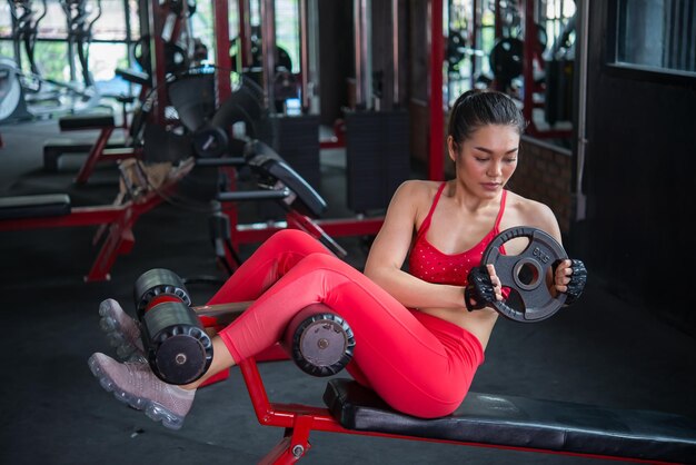 Beautiful asian woman play fitness in the gymThailand girl has a slim bodyTime for exercisePeople love heathLift up the plate on the bench