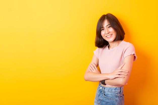 Beautiful asian woman posing on yellow wall with copyspace