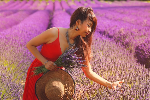 Bella donna asiatica in vestito rosso sul campo di lavanda