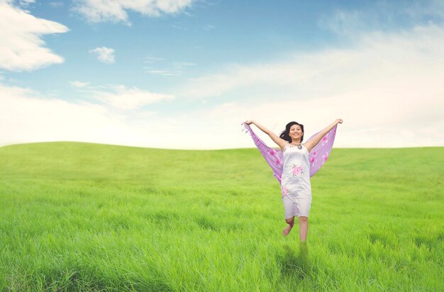 Beautiful asian woman running on field summer or spring concept