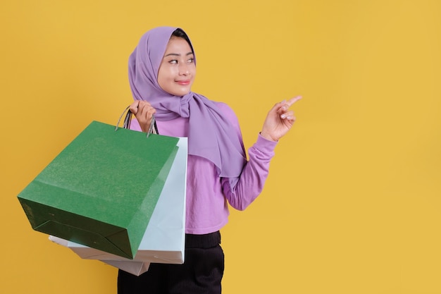 Beautiful asian woman showing shopping bags, wearing purple T shirt cheerful and joyful