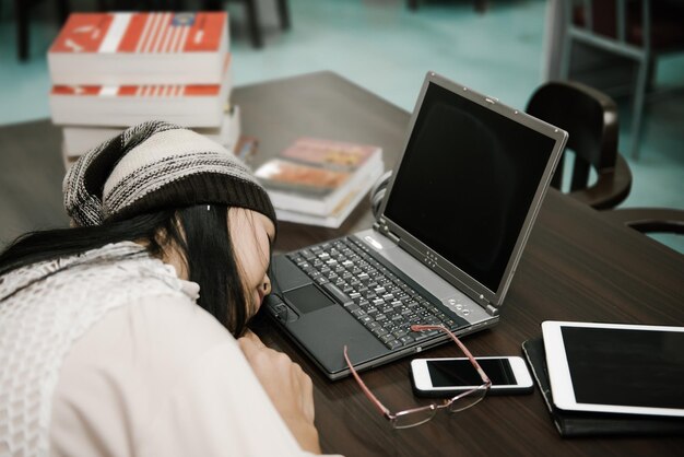 Beautiful asian woman sleep on the desk with laptop in the library