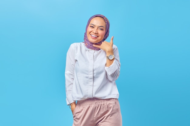 Beautiful Asian woman smiling doing call gesture with hand