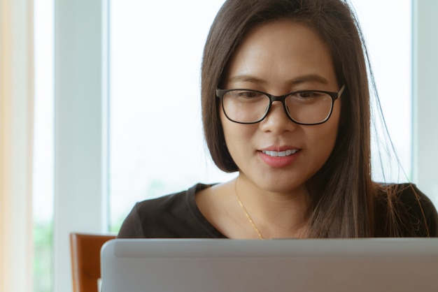 Beautiful asian woman smiling and looking at laptop screen