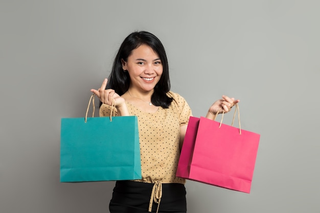 Beautiful asian woman smiling while holding shopping bags