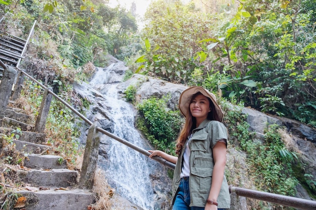 A beautiful asian woman standing in front of waterfall